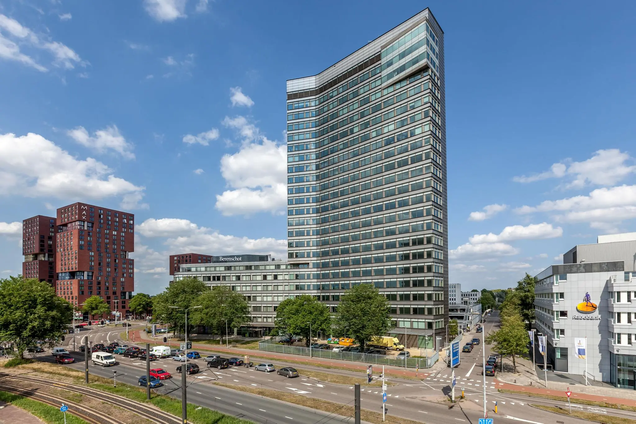 Hoog kantoorgebouw aan de Vliegend Hertlaan in Utrecht met omliggende wegen, verkeer en andere kantoren onder een blauwe lucht.